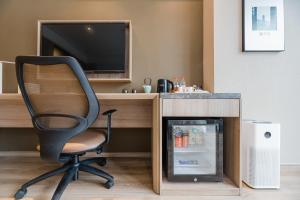 a office with a desk and a chair and a refrigerator at Atour Hotel Taizhou Linhai Branch in Linhai