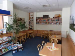 a dining room with tables and chairs and bookshelves at Sleep & Go Hotel Magdeburg in Magdeburg