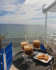 uma mesa com duas bebidas e um prato de pastelaria em Olympos Beach em Plaka Litochorou
