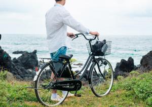 a man riding a bicycle on top of a lush green hillside at Playce Camp Jeju in Seogwipo
