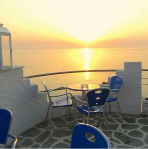 una mesa y sillas en un balcón con vistas a la puesta de sol en Olympos Beach en Plaka Litochorou