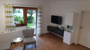een woonkamer met een televisie, een tafel en een stoel bij LaWie am Attersee in Alexenau
