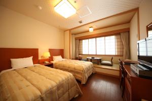 a hotel room with two beds and a television at Hotel Tappi in Satogahama