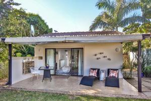 uma casa com um pátio com uma mesa e cadeiras em Kingsley House Chalet em Ballito