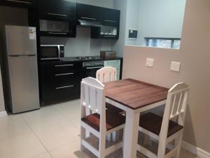 una cucina con tavolo in legno e 2 sedie di Field's Rest: The Apartment a Port Elizabeth