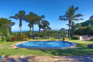 a swimming pool in a yard with palm trees at Kingsley House Chalet in Ballito