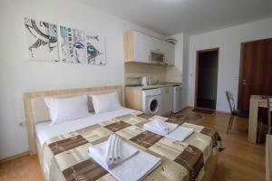 a bedroom with a large bed with two napkins on it at Tiffany Joy Apartments in Primorsko