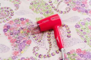 a red blow dryer sitting on a table with flowers at ROOMs六本松03 in Fukuoka