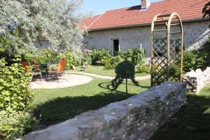 een tuin met een stenen muur en een tafel en stoelen bij les agnates in Flagey-Échézeaux