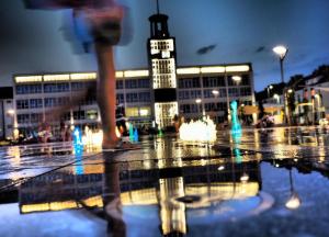 a person walking in front of a building with a fountain at Nocleg 62 Koszalin in Koszalin