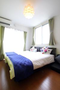a bedroom with a large bed and two windows at Chura Minpaku Ishigaki in Ishigaki Island