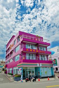 鵝鑾的住宿－品喬旅店，粉红色的建筑,在街上写着