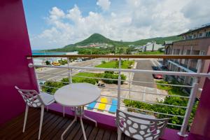 a balcony with a table and chairs and a view of the ocean at Pin Ciao Hostel in Eluan