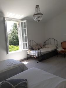 a bedroom with two beds and a window at Aux Roses de l'Etang in Capestang