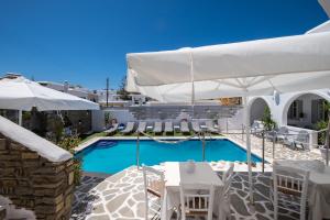a swimming pool with white tables and white umbrellas at Joseph Studios in Naousa