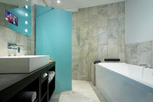 a bathroom with a large white sink and a blue wall at Mainport Design Hotel in Rotterdam