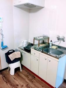 eine Küche mit einer Spüle und einer Theke mit einem Stuhl in der Unterkunft Yoron Tandy-House in Yoron