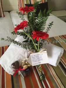 a vase filled with red flowers on a bed at Agro-Turismo do ROXO in Santa Vitória