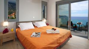 a bedroom with a large orange bed with a balcony at Luxury Villas Kefalonia in Trapezaki