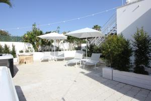 un patio con sillas y sombrillas blancas en VILLA ROSA, en Torre Suda