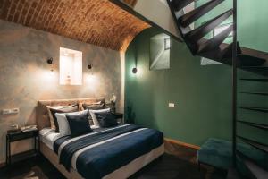 a bedroom with a bed with green walls and a staircase at House of LoftAffair in Krakow