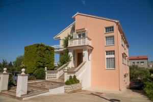 ein rosa Haus mit Treppe und Balkon in der Unterkunft F• R• I• E• N• D• S• in Novalja