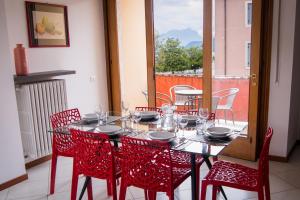 a dining room table with red chairs and a window at Appartamento DAISY in Bardolino