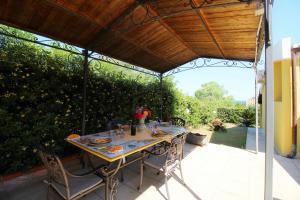 stół i krzesła pod pergolą na patio w obiekcie Villa Azzurra nel centro di Costa Rei w mieście Costa Rei