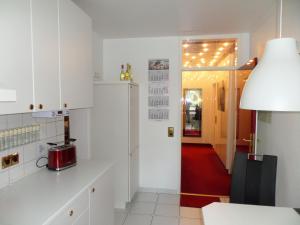 uma cozinha com armários brancos e um tapete vermelho em Rot-Weiss em Bad Zwischenahn