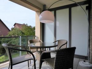 Una mesa y sillas en un balcón con ventana. en Apartment Seerose, Am Alten Deich 14, Haus 2 Whg. 6 (Parkplatz 27), en Dangast