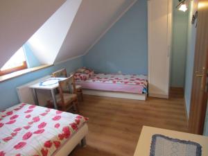 um quarto no sótão com 2 camas, uma mesa e uma janela em Ostoja w Lipowcu em Jaśliska