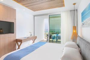 a bedroom with a bed and a tv and a balcony at Limanaki Beach Hotel & Suites in Ayia Napa
