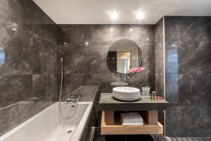 a bathroom with a tub and a sink and a mirror at Limanaki Beach Hotel & Suites in Ayia Napa
