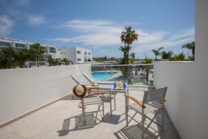 a balcony with a table and chairs and a swimming pool at Limanaki Beach Hotel & Suites in Ayia Napa