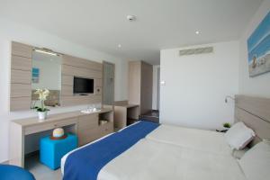 a bedroom with a bed and a sink and a mirror at Limanaki Beach Hotel & Suites in Ayia Napa