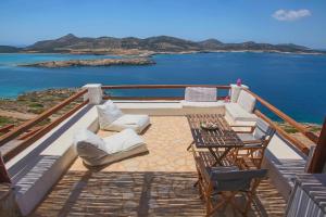 a balcony with chairs and a table and the ocean at Antiparos Vibes in Agios Georgios