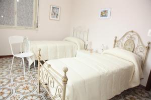 2 camas en una habitación blanca con mesa y silla en CASA VACANZE FRANCESCO E TANINA, en Nicolosi