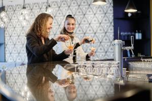 two women sitting at a table drinking wine glasses at Sorell Hotel Ador in Bern