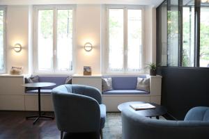 uma sala de espera com cadeiras, um sofá e janelas em Stella Etoile em Paris