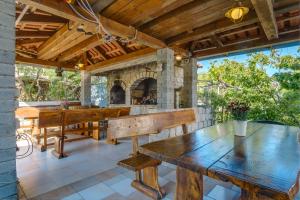 an outdoor patio with wooden tables and a stone fireplace at Apartmani Maris in Mali Lošinj
