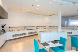 a kitchen with a table and blue chairs at Limanaki Beach Hotel & Suites in Ayia Napa