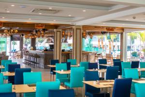 a restaurant with blue chairs and tables and a bar at Limanaki Beach Hotel & Suites in Ayia Napa