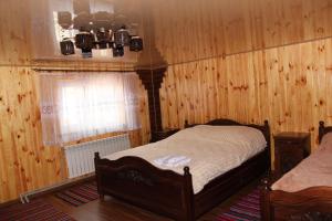 1 dormitorio con paredes revestidas de madera, 1 cama y ventana en Карпатське сяйво, en Vizhni Siniyvir