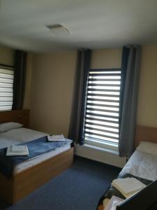 a bedroom with two beds and two windows at Motel BZ in Siewierz