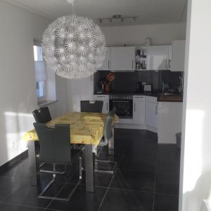 a kitchen with a dining table with chairs and a chandelier at DHH Claire_SAWO in Ostseebad Karlshagen