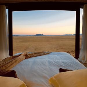 Bett in einem Zimmer mit Blick auf die Wüste in der Unterkunft Desert Whisper in Solitaire