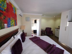 a bedroom with a large white bed with purple pillows at Lucolo Palace B&B - Mthatha in Mthatha