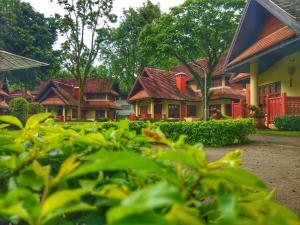 um grupo de casas com telhados vermelhos e árvores em Suan Bua Hotel & Resort em Ban Pong