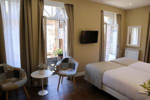 een hotelkamer met een bed en twee ramen bij VÍA XIX in Caldas de Reis