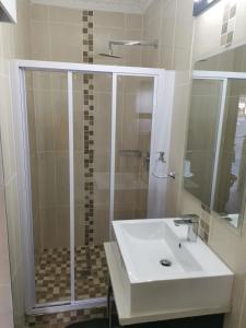 bagno con doccia e lavandino bianco di Lucolo Palace B&B - Mthatha a Mthatha